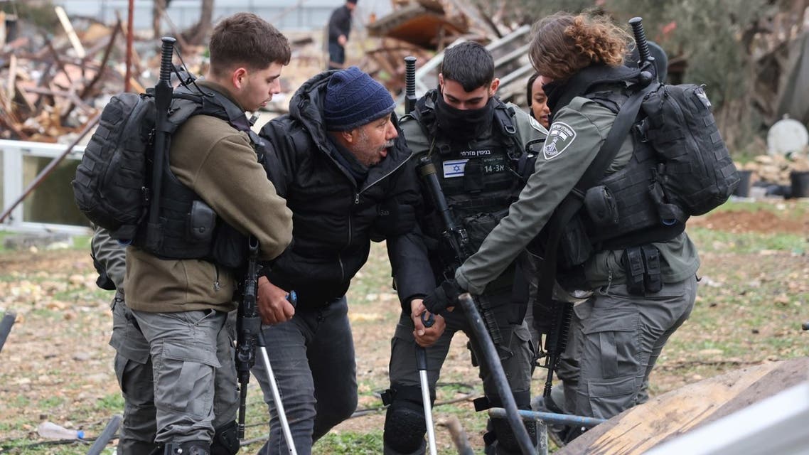 Israeli forces escort a man on crutches away from the ruins of a Palestinian house they demolished, in Sheik Jarrah neighborhood on January 19, 2022. (AFP)