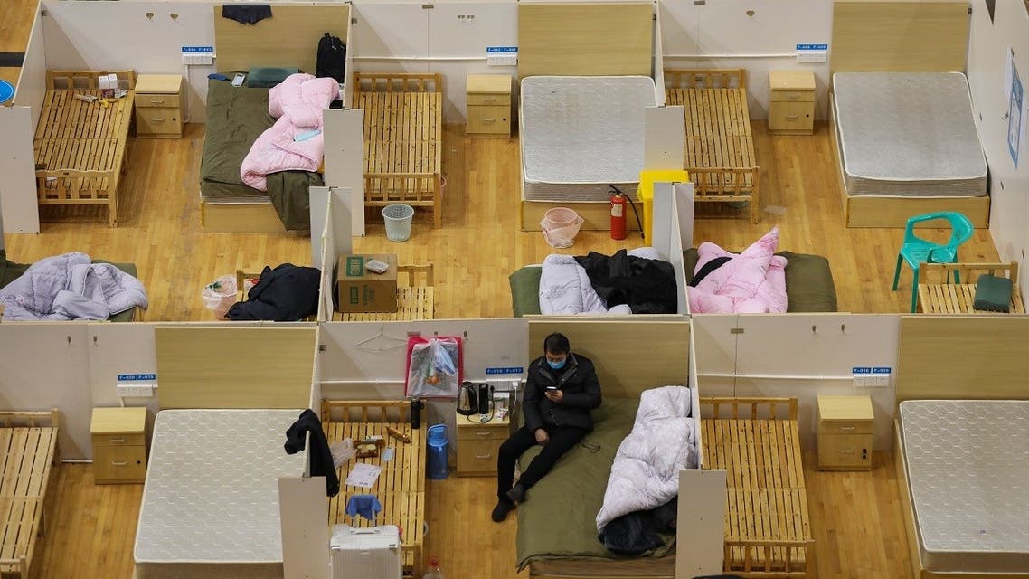 This photo taken on March 5, 2020 shows a medical worker (top L) walking past empty beds as a patient rests at a temporary hospital set up for COVID-19 coronavirus patients in a sports stadium in Wuhan, in China's central Hubei province. (AFP/STR)