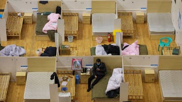 This photo taken on March 5, 2020 shows a medical worker (top L) walking past empty beds as a patient rests at a temporary hospital set up for COVID-19 coronavirus patients in a sports stadium in Wuhan, in China's central Hubei province. (AFP/STR)