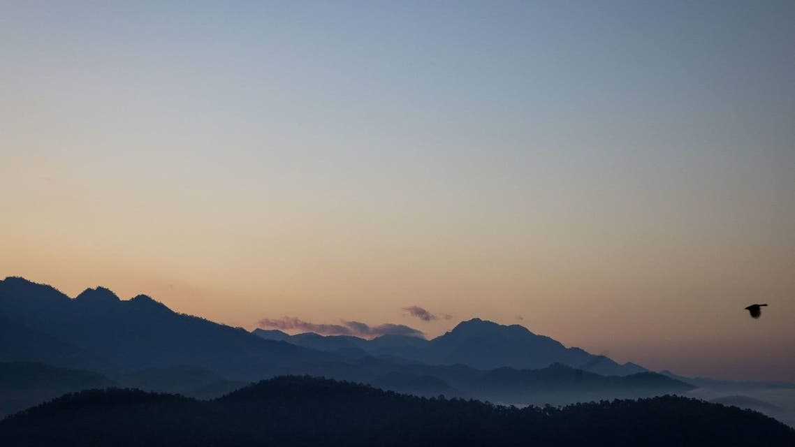 A bird flies past as the sun begins to rise behind the mountains in Mae Hong Son on January 2, 2022. (AFP)