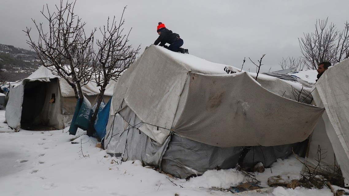 A young Syrian boy clears the snow covering a tent at a camp for internally displaced people in Idlib, Jan. 23, 2022. (AFP)