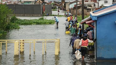 People walk through flood water after several houses were affected by rising water following heavy rains in 67 Hectares neighbourhood in Antananarivo on January 24, 2022. (AFP)