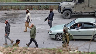 Israeli settlers, some armed, walk down a road near the West Bank village of Burqah on December 17, 2021, after reported attacks by Israeli settlers on the village. Israeli soldiers carried out a massive manhunt in the occupied West Bank after a Palestinian shooting attack on a car that resulted in one Israeli dead and two others wounded. (Photo by JAAFAR ASHTIYEH / AFP)