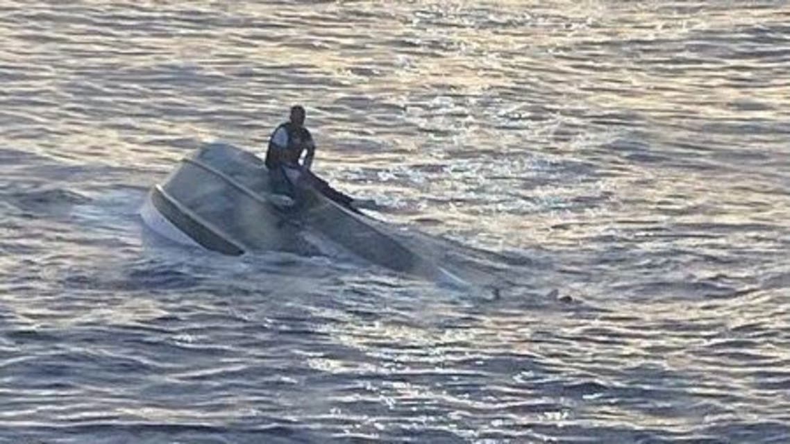 A man, who says he was one of 40 people who left Bimini, Bahamas, on Saturday before encountering severe weather, sits on a capsized boat off the coast of Fort Pierce Inlet, Florida, U.S., in this photo released by the U.S. Coast Guard on January 25, 2022. Courtesy of U.S. Coast Guard/Handout via REUTERS