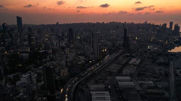 A dusk aerial view of cars driving by the devastated Port of Beirut, in darkness during a power outage. (File Photo: AFP)