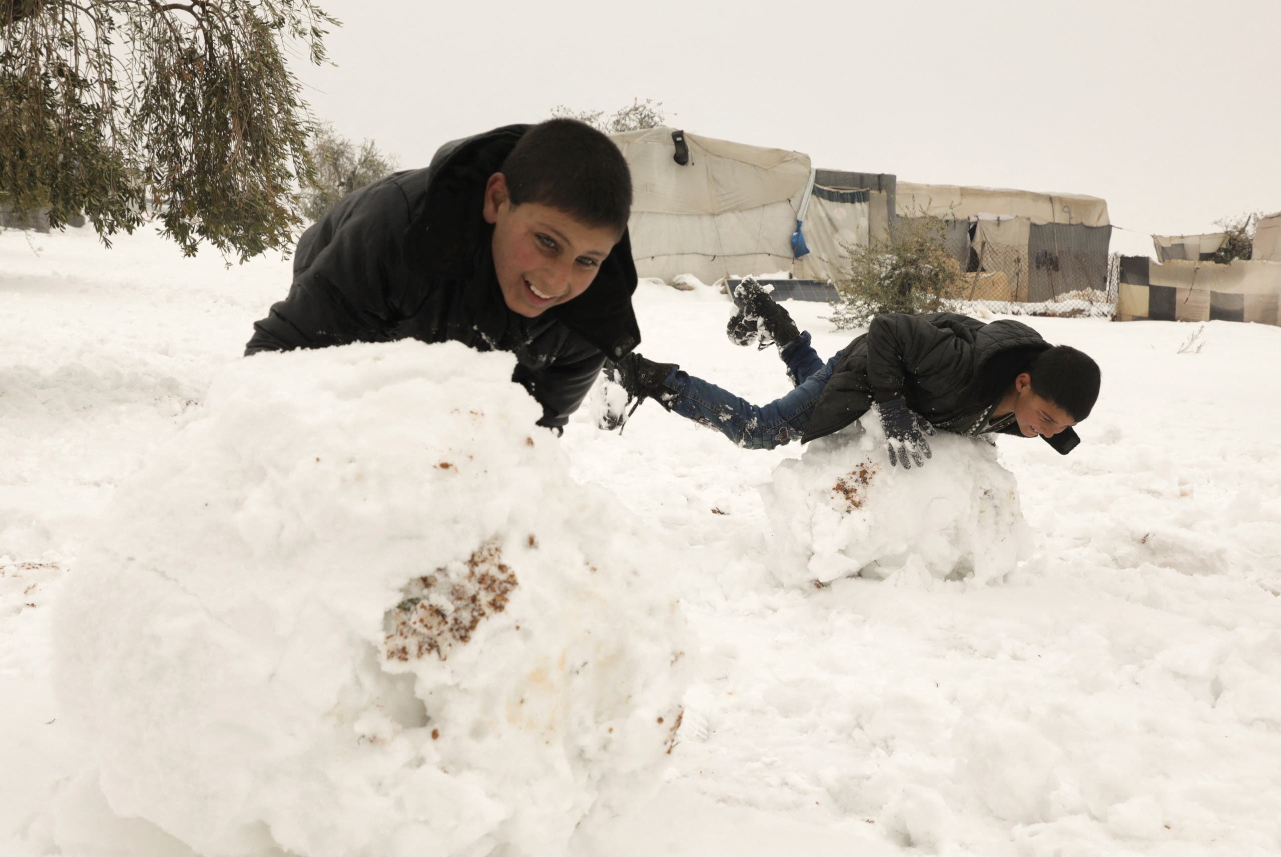 Internally displaced boys play together in the snow at a camp in Aleppo countryside, Syria, January 23, 2022. (Reuters)