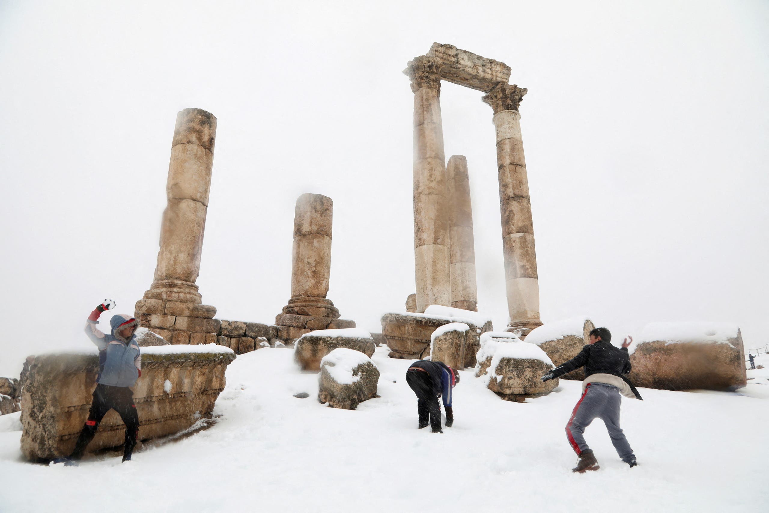 Boys play with snow at the pillars of the Roman Temple of Hercules at Amman Citadel, an ancient Roman landmark, covered in snow in Amman, Jordan January 27, 2022. (Reuters)