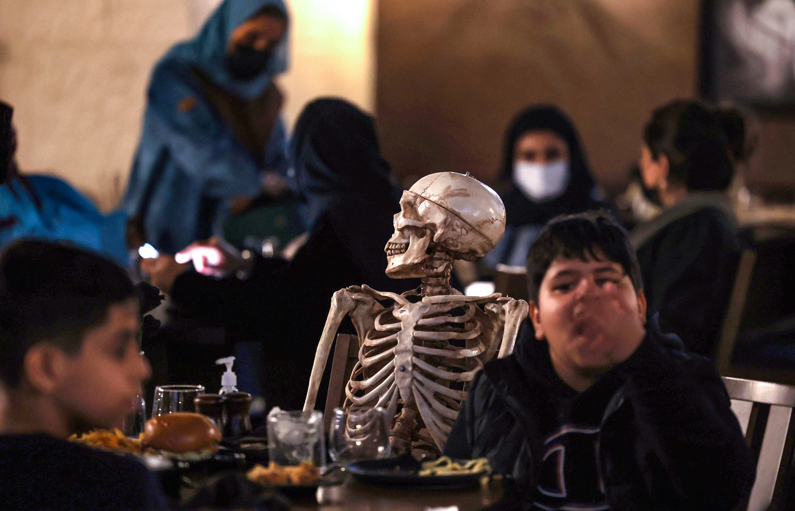 A skeleton model is seated at a table with diners at the horror-themed Shadows restaurant Boulevard Riyadh City, late on January 19, 2022. (AFP)