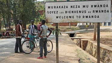 People stand by a placard reading Welcome to Rwanda in Akanyaru on the Rwandan side of the street located at the border with Burundi, on August 23, 2016. (AFP)