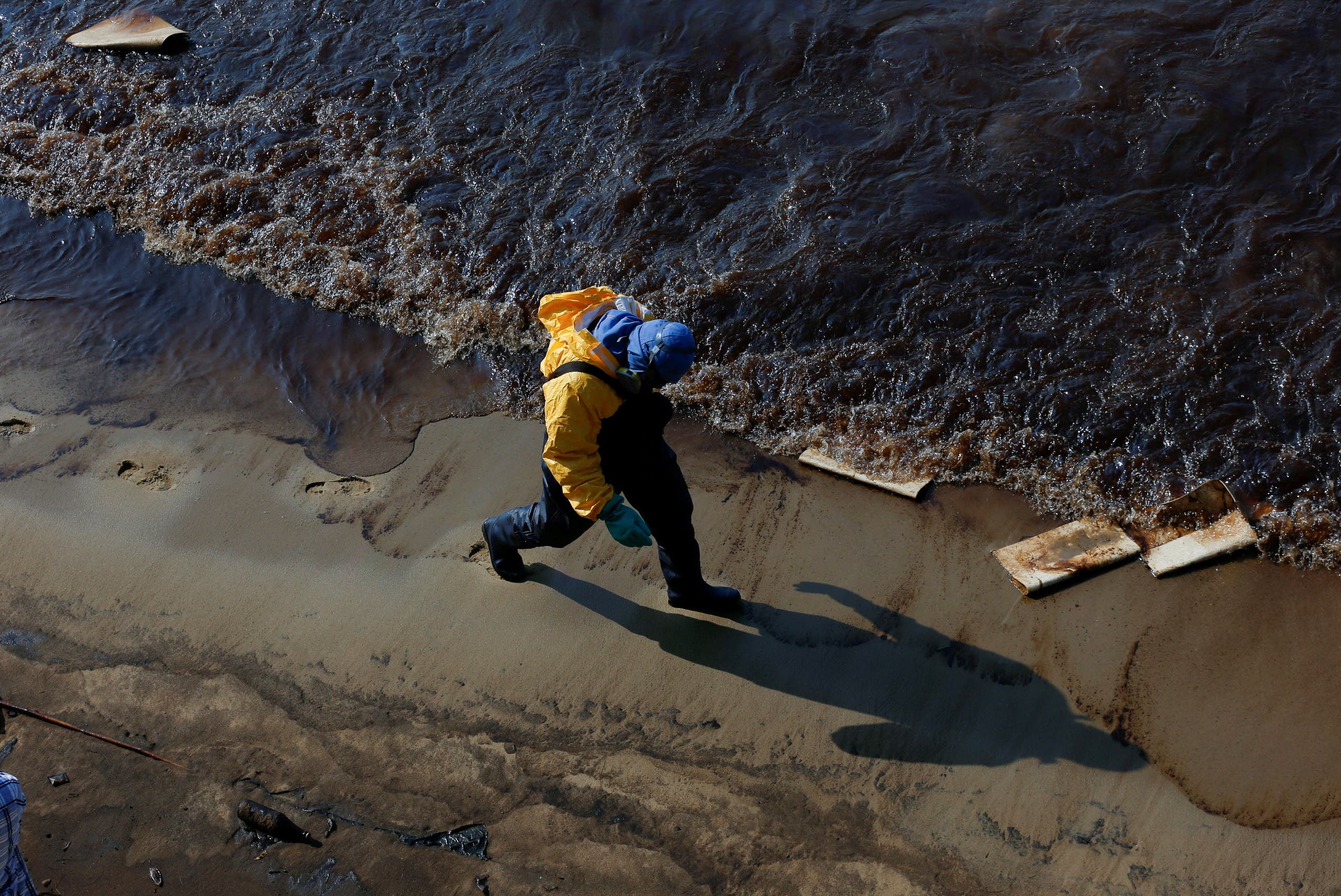 A worker cleans oil spills caused by a leak from an undersea pipeline 20 km (12.4 miles) off Thailand's eastern coast at Mae Ramphueng beach in Rayong province, Thailand, January 29, 2022. (Reuters)
