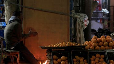 An Egyptian street vendor warms up by a fire in front of a shop selling fruit at the road in Toukh, Al Qalyubia Governorate, north of Cairo, Egypt. (Reuters)