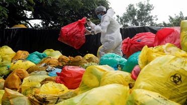 A man in personal protective equipment (PPE) clears bags filled with medical waste at a hospital, amidst the spread of the coronavirus disease (COVID-19) in Mumbai, India, August 11, 2020. (Reuters)