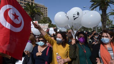 Tunisians lift placards as they demonstrate against the government and police repression in the capital Tunis on February 6, 2021, at a rally in commemoration of the 8th anniversary of the assassination of prominent leftist opposition leader Chokri Belaid (balloon portrait). / AFP / FETHI BELAID