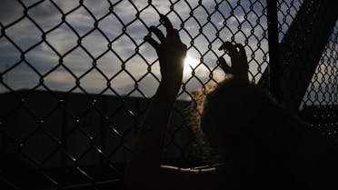 File photo shows a person clinging on to a chain link fence.