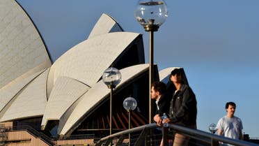 People stand near the Opera House in Sydney on August 14, 2021, as Australia's biggest city announced tighter Covid restrictions including heavier fines and tighter policing to contain a Delta outbreak. (Photo by Saeed KHAN / AFP)