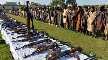 In this photograoh taken on November 17, 2019 members of the Islamic State (IS) group stand alongside their weapons, following they surrender to Afghanistan's government in Jalalabad, capital of Nangarhar Province. Over 225 Islamic state IS militants including their families 190 women and 208 children were surrendered to government during past two weeks, Afghan security forces lunched a military operation against ISIS in Achin district of Nangarhar province, Nangarhar governor Shamahmod miakhil said. / AFP / NOORULLAH SHIRZADA