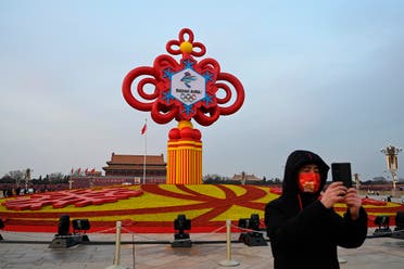 A man records video footage in front of an installation displaying a Chinese knot with the logo of the Beijing 2022 Winter Olympics at Tiananmen Square in Beijing on January 19, 2022. (AFP)