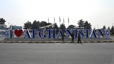 Taliban fighters stand next to a sign installed outside the Kabul airport in Kabul on February 5, 2022. (Photo by Wakil KOHSAR / AFP)