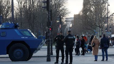 People walk past armoured vehicles from the French Gendarmerie in place along a street near the Champs Elysees avenue in Paris as French anti-COVID restrictions car drivers and their Convoi de la liberte (The Freedom Convoy), a vehicular convoy protest underway to Paris to protest coronavirus disease (COVID-19) vaccine and restrictions in France, February 11, 2022. (Reuters)