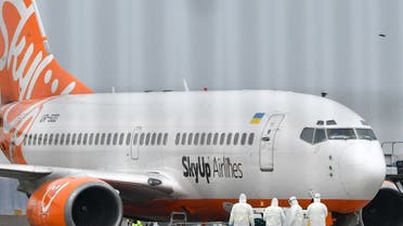 A picture taken on February 20, 2020 through a fence at the Kiev international airport Boryspil, shows airport crew members and emergency services in protective clothing checking the fuselage of a Boeing 737 aircraft of SkyUp Airlines, during a stopover following the evacuation of Ukrainians and foreign nationals from the Chinese city of Wuhan, the centre of the deadly coronavirus outbreak. (AFP)