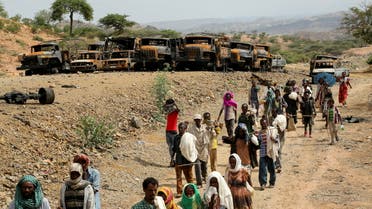 Villagers return from a market to Yechila town in south central Tigray walking past scores of burned vehicles, in Tigray, Ethiopia, July 10, 2021. (File photo: Reuters)