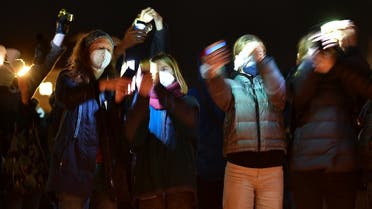 People hold up their phones with flashlights on in protest against coronavirus disease (COVID-19) deniers at Odeonsplatz in Munich, Germany, on February 10, 2022. (Reuters)