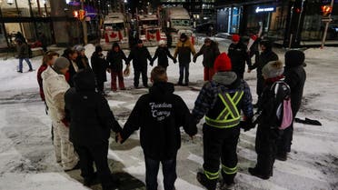 People stand in circle and say the Lord's Prayer as truckers and supporters continue to protest coronavirus disease (COVID-19) vaccine mandates, in Ottawa, Ontario, Canada, February 18, 2022. (Reuters)