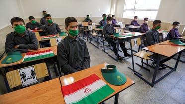 School children sit together in a classroom while mask-clad and distanced apart from each other, new COVID-19 coronavirus pandemic school precautions, with Iranian national flags on the desk of each, on the first day of schools re-opening, at Nojavanan school in the capital Tehran on September 5, 2020. / AFP / ATTA KENARE  iran - education - health - virus  iran - education - health - virus  iran - education - health - virus