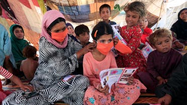  An internally displaced woman helps a girl put on a face mask distributed by UNICEF, at a makeshift camp, amid the coronavirus outbreak, in Jalalabad, Afghanistan, on June 22, 2020. (Reuters)