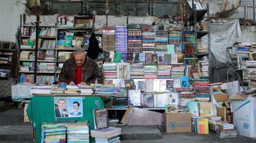 Abu Osama, sits at his sidewalk stall selling second-hand books in Damascus, Syria, February 17, 2022. (Reuters)