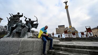 A man wrapped with an Ukrainian national flag sits at Maidan Independence Square in Kyiv, Feb. 24, 2022. (AFP)