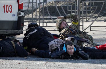 People take cover as an air-raid siren sounds, near an apartment building damaged by recent shelling in Kyiv, Ukraine February 26, 2022. (Reuters)
