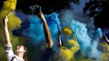 People hold flares with the colors of the Ukrainian flag as Ukrainians and supporters hold an anti-war protest outside the Russian Embassy, following Russia's invasion of Ukraine, in Mexico City, Mexico February 28, 2022. (Reuters)