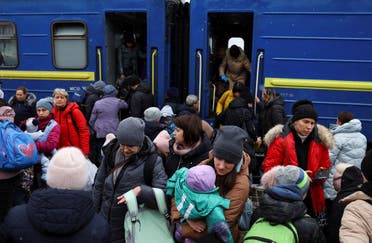 أشخاص ينتظرون قطاراً متجهاً إلى بولندا بمحطة القطار في لفيف (رويترز)