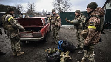 TOPSHOT - Ukrainian soldiers unload weapons from the trunk of an old car, northeast of Kyiv on March 3, 2022. A Ukrainian negotiator headed for ceasefire talks with Russia said on March 3, 2022, that his objective was securing humanitarian corridors, as Russian troops advance one week into their invasion of the Ukraine. (Photo by Aris Messinis / AFP)