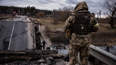 An Ukrainian serviceman looks at a civilian crossing a blown up bridge in a village, east of the town of Brovary on March 6, 2022. (AFP)