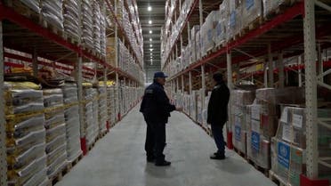 World Health Organization staff talk among warehouse shelves stacked with aid supplies, following Russia's invasion of Ukraine, in Lviv, Ukraine, March 7, 2022, in this still image taken from video. (WHO, Reuters)