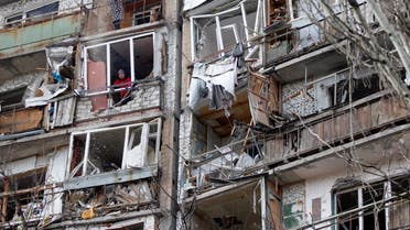 A resident uses a dustpan and broom (top) to clear the debris from a flat, as another looks out of the destroyed front of a room, in a multi-storey building that was badly damaged as a result of Russian missile explosion after it was shot down over the city by Ukrainian air defense on March 6, in Kramatorsk on March 7, 2022. (AFP)