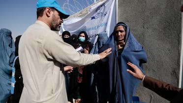 An UNHCR worker explains aid collection procedures to displaced Afghan women, outside a distribution center on the outskirts of Kabul, Afghanistan October 28, 2021. (Reuters)