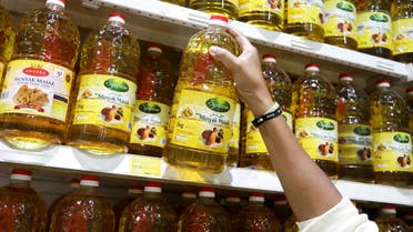 A person holds bottles of cooking oil made from oil palms at a supermarket in Subang Jaya, Malaysia, March 8, 2022. (Reuters)