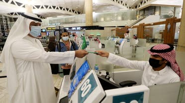 A Saudi man wearing a face mask gets his passport from a Saudi Immigration officer, at the King Khalid International Airport, May 16, 2021. (File photo: Reuters)