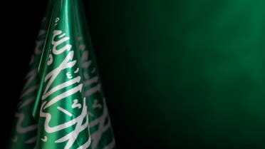 Saudi Arabia flags on left side with a dark green background. stock photo