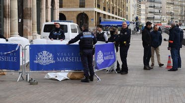 French police officers stand next to the body of an unidentified man (L) who attempted to stab French municipal police officers, outside the city hall in Marseille, southern France, on March 12, 2022. (AFP)