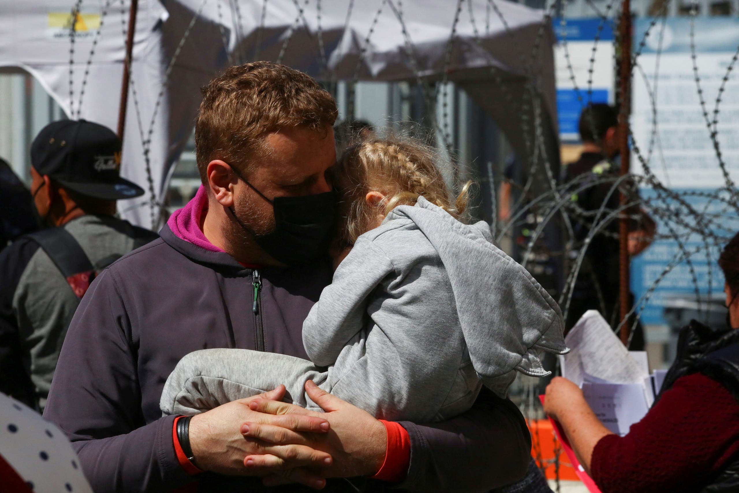 A Ukrainian man embraces his daughter while waiting with his family for a humanitarian visa outside the San Ysidro Port of Entry of the U.S.-Mexico border in Tijuana, Mexico March 11, 2022. (Reuters)