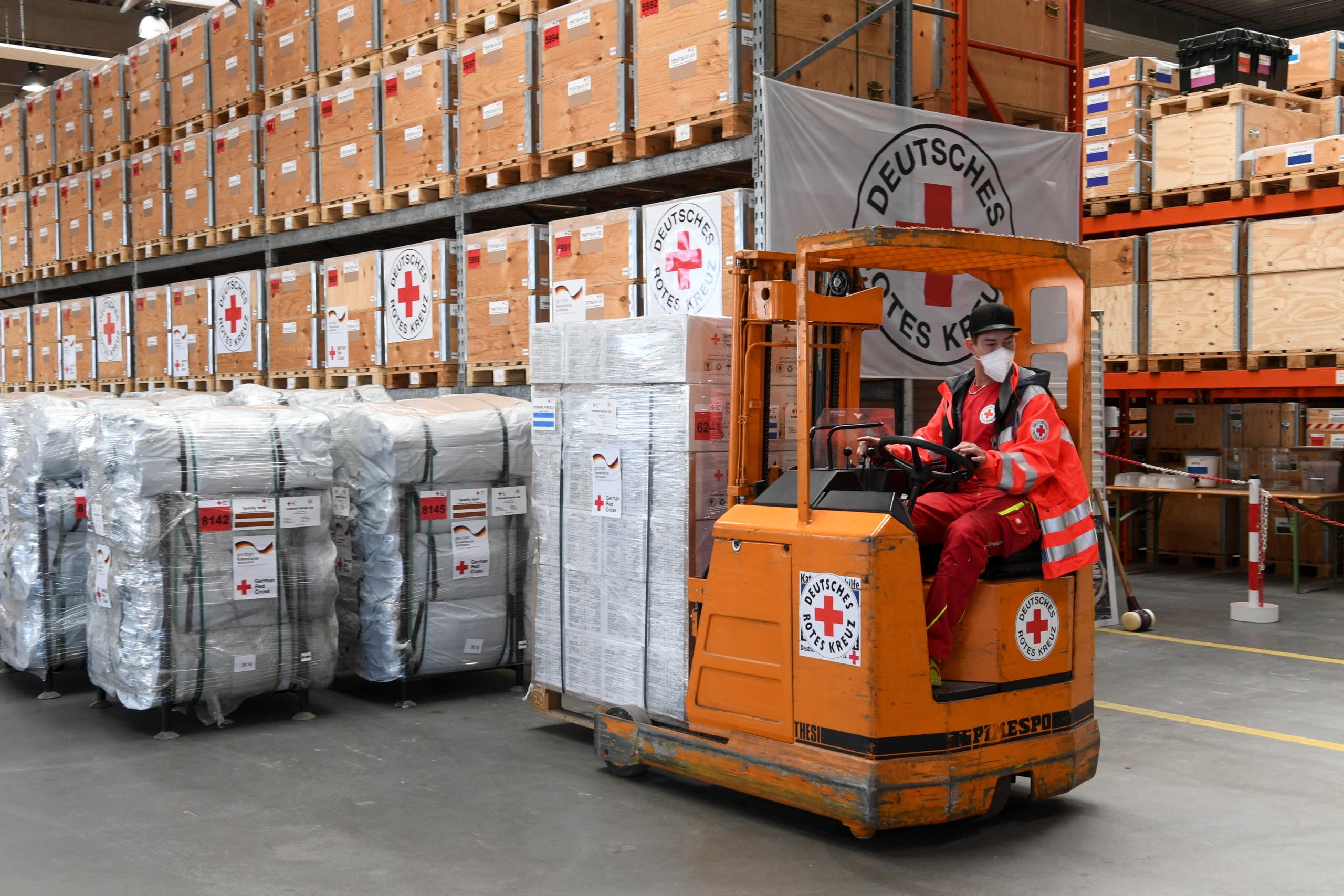 A German Red Cross (DRK) employee operates a forklift with humanitarian supplies to load for a first aid transport to Poland for those fleeing Russia's invasion in Ukraine, at the DRK logistics center in Schoenefeld near Berlin, Germany, March 1, 2022. (Reuters)