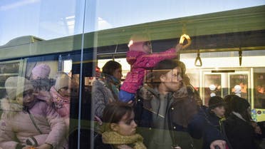 People with children are seen in a bus for refugees fleeing Russia's invasion of Ukraine, in Lviv, Ukraine, March 13, 2022. Picture taken through a glass window. (Reuters)