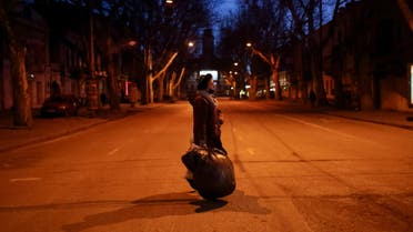 A woman carries a bag with clothes as she walks on a street before curfew, as Russia's invasion of Ukraine continues, in downtown Odessa, Ukraine, March 12, 2022. (Reuters)