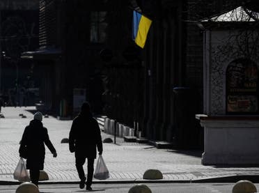 Locals residents walk on an empty street carrying bags with food, as an Ukrainian national flag is seen in central Kyiv, Ukraine March 10, 2022. (Reuters)