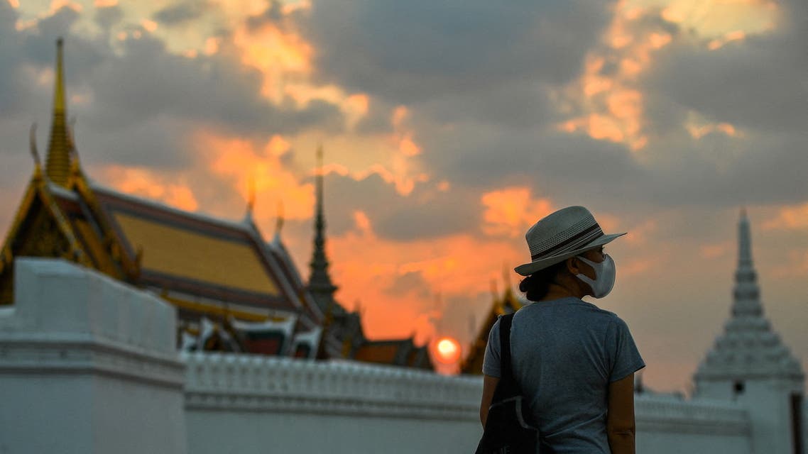 A tourist wears a face mask to prevent spread of the coronavirus disease (COVID-19) during sunset near the Grand Palace in Bangkok, Thailand, January 7, 2022. (Reuters)