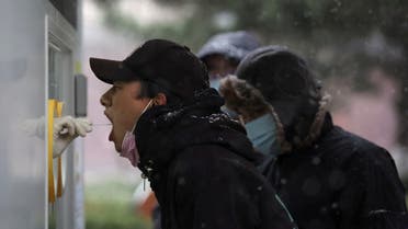 A man has his swab sample taken at a mobile nucleic acid testing site, following the coronavirus disease (COVID-19) outbreak, on a snowy day in Beijing, China March 18, 2022. (Reuters)